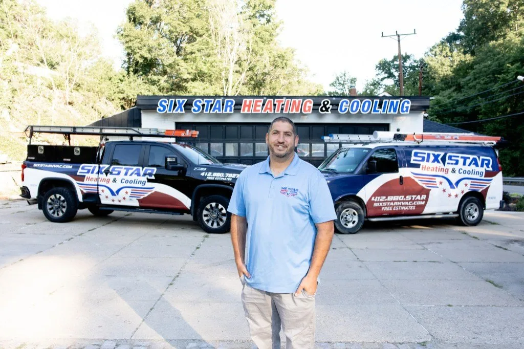 AJ Laugelli, founder and president of Six Star Heating & Cooling, outside the Carnegie shop with branded service trucks.