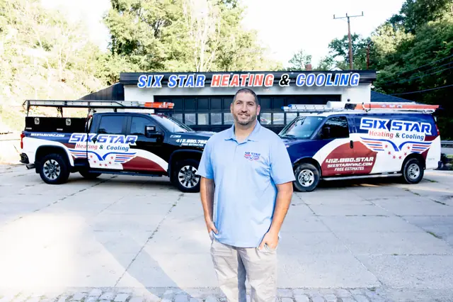 AJ Laugelli, founder of Six Star Heating & Cooling, in front of the Carnegie shop and branded fleet.